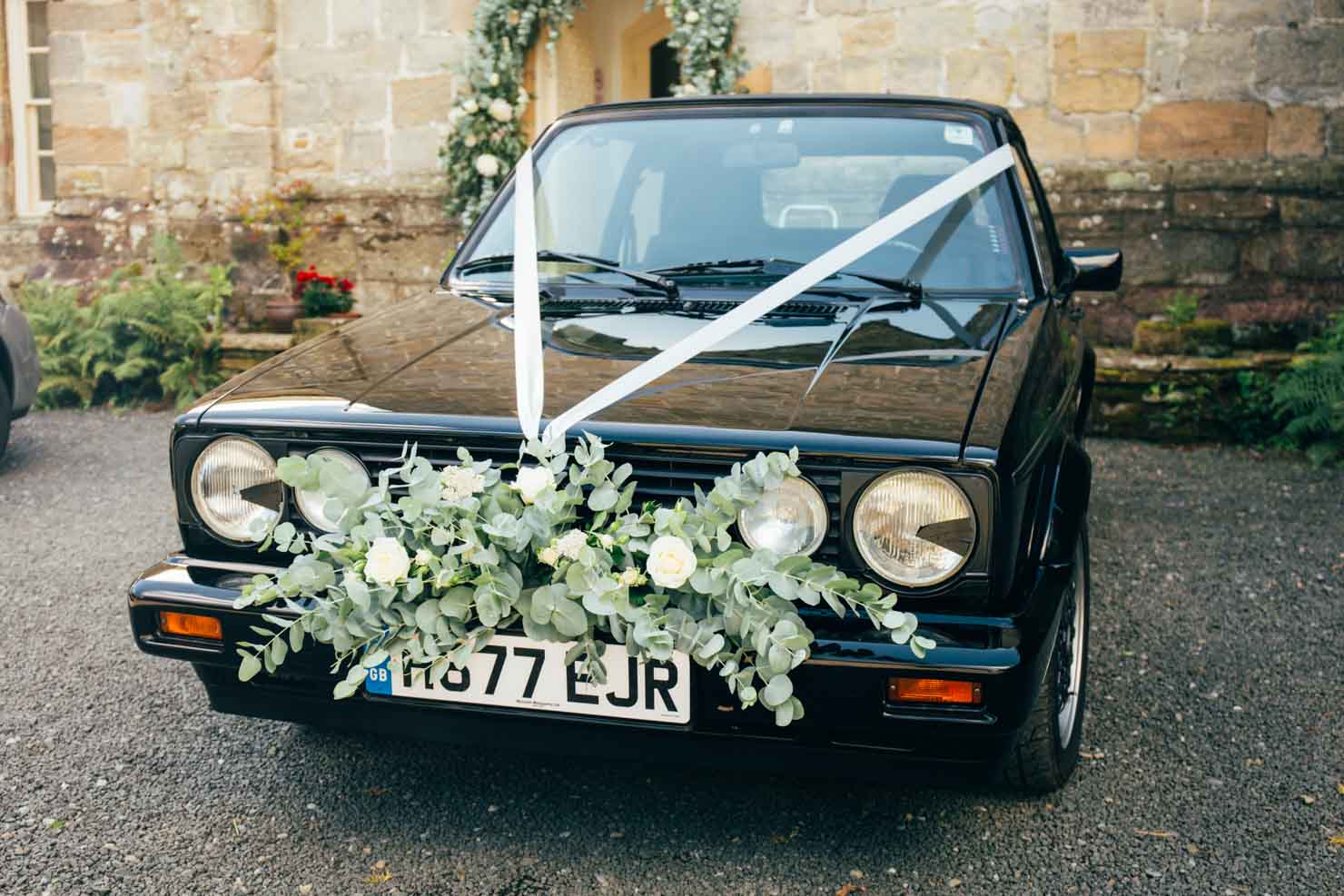 black golf cabriolet wedding car with flowers