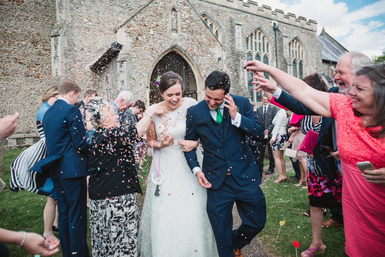 Photography of relaxed bride and groom during confetti throw outside church