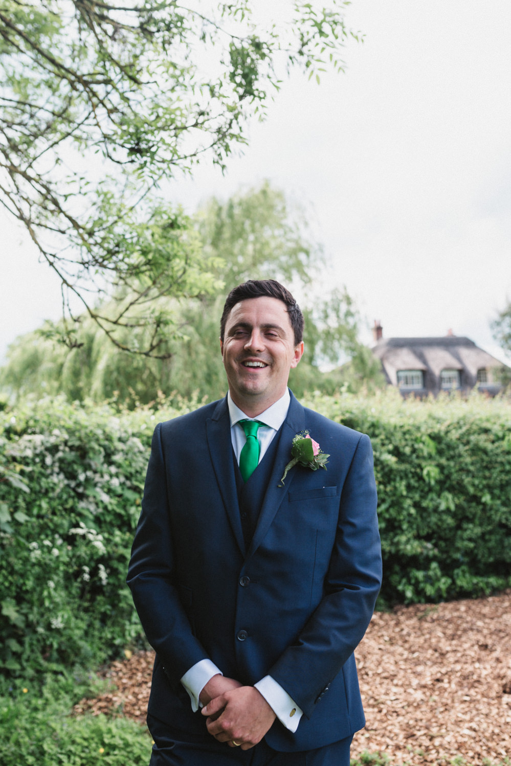 Relaxed groom portraits in front of water by norfolk wedding photographer emily tyler