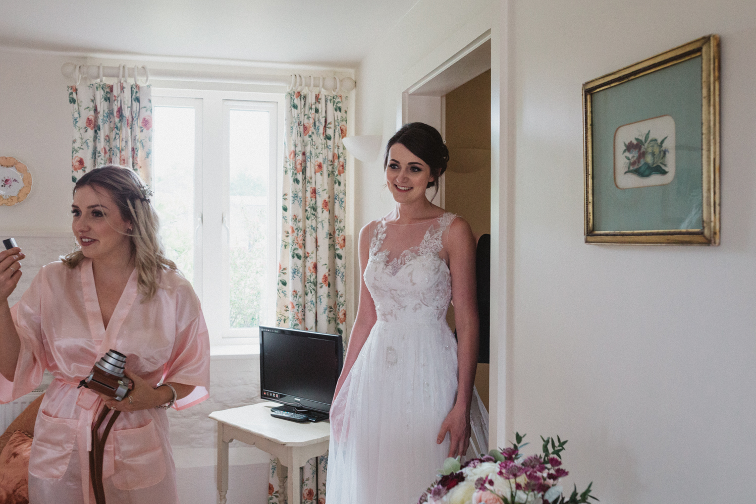 photography of bride putting on her dress at a natural pretty elms barn wedding in suffolk