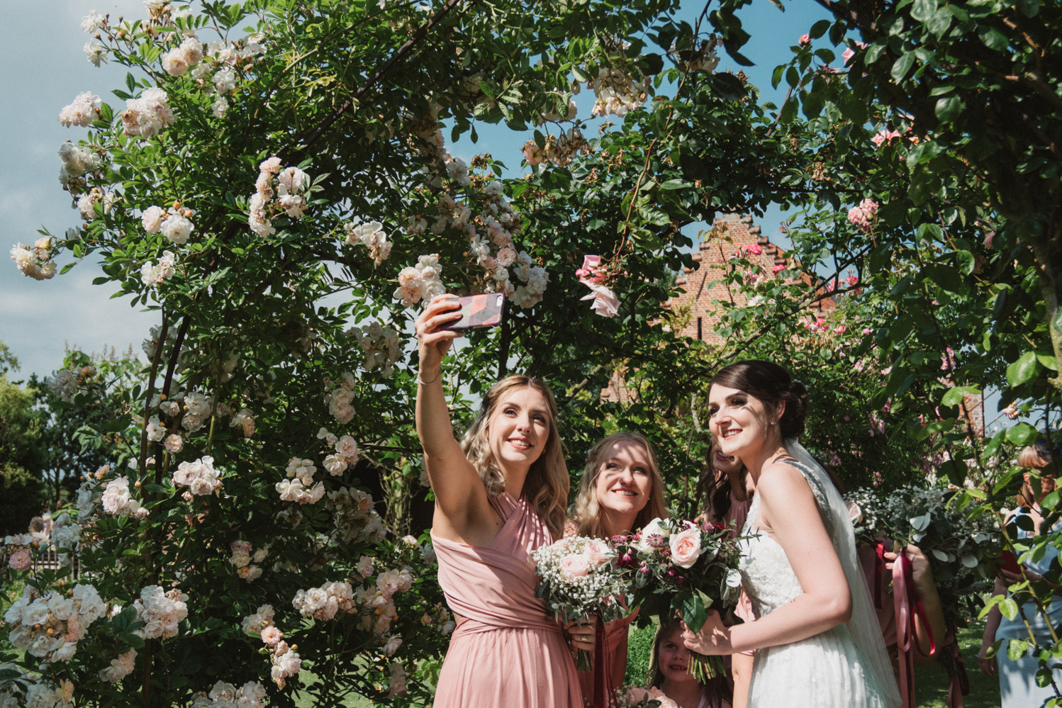 photography of bride and pink bridesmaids at a natural pretty elms barn wedding in suffolk