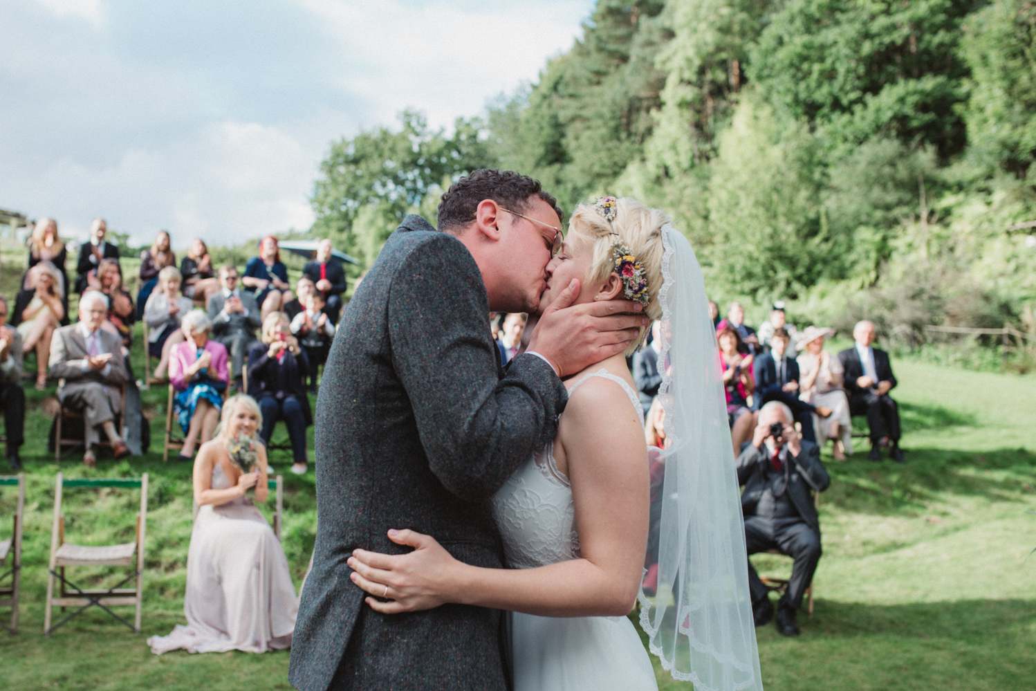 bohemian bride and groom kiss during outdoor ceremony keeper and the dell wedding in norfolk