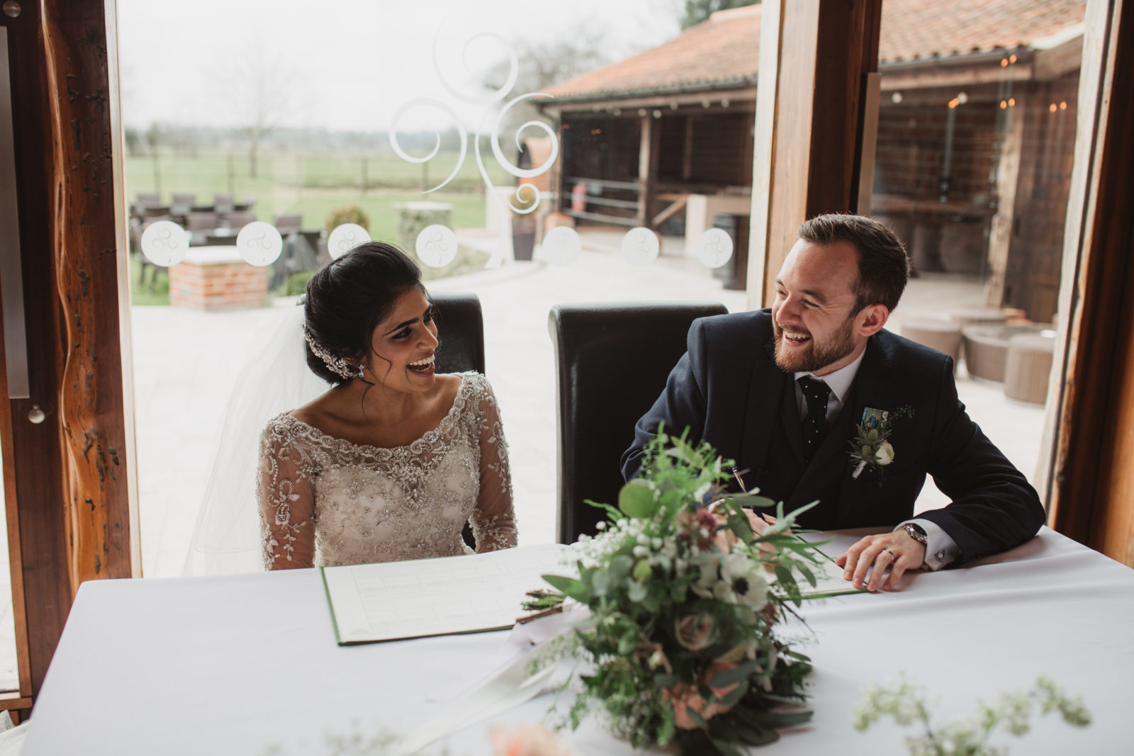 relaxed laughing norfolk couple signing wedding register at southwood hall