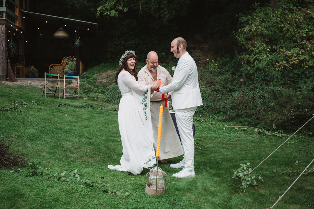 bride and groom dressed in white for pagan hand fasting ceremony outdoors