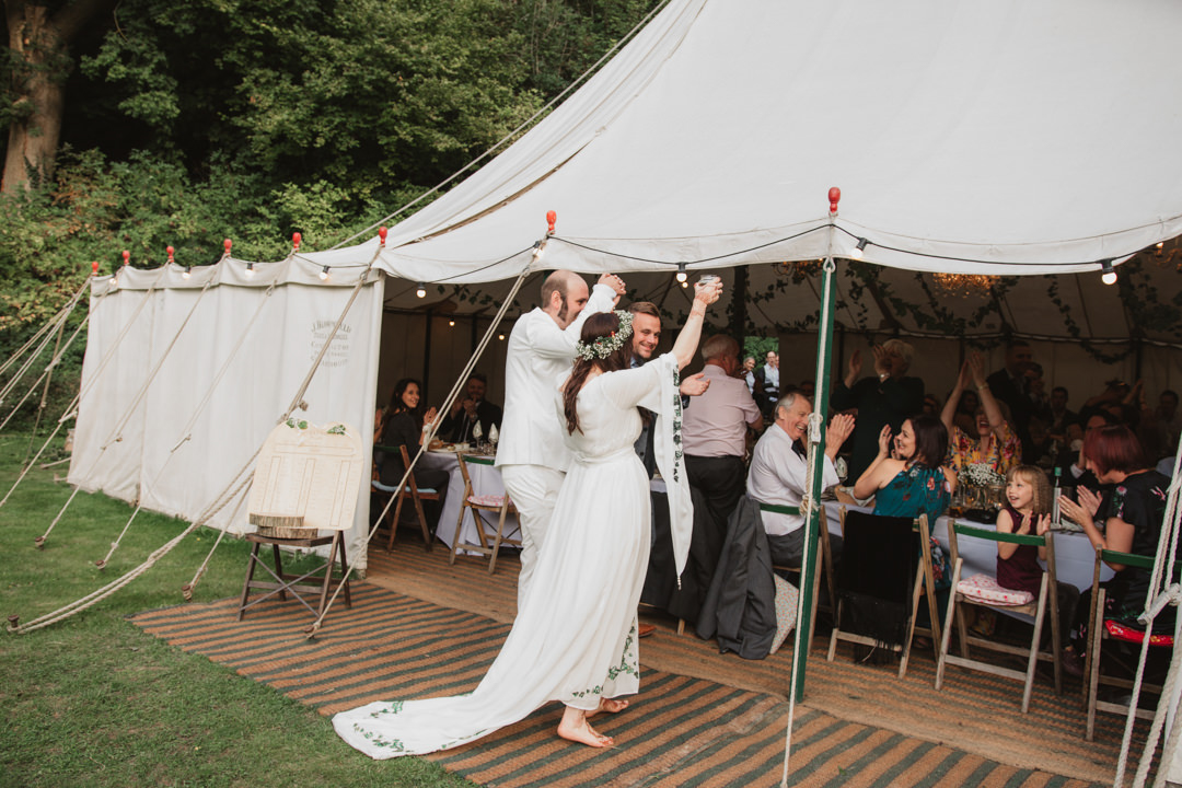 bride and groom in white entering keeper and the dell vintage marquee