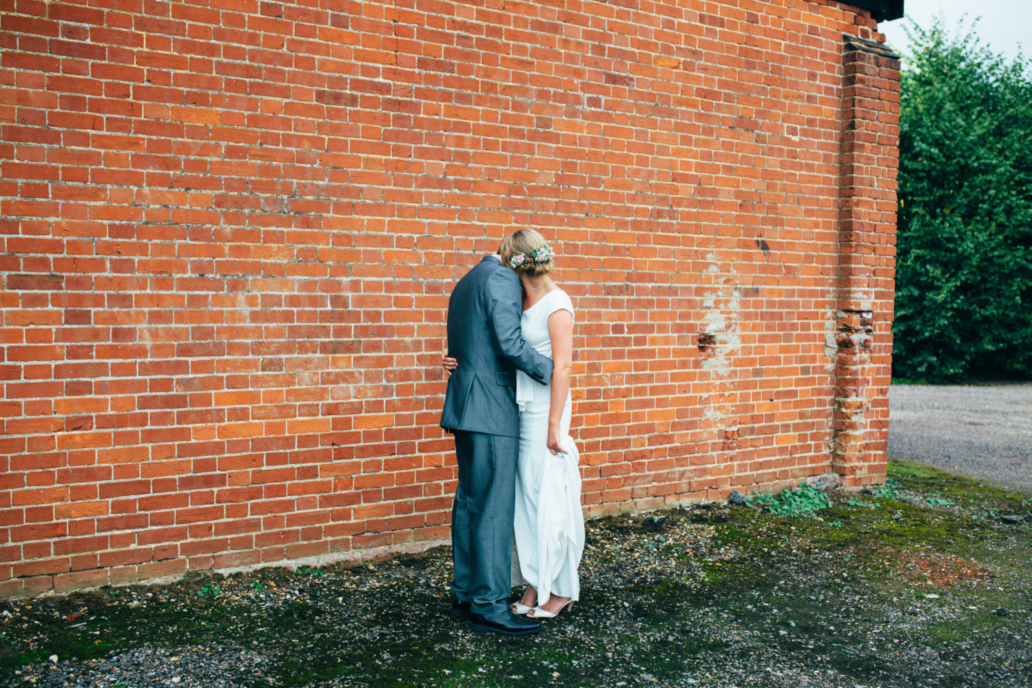 couple kissing outside red brick barn wedding in suffolk