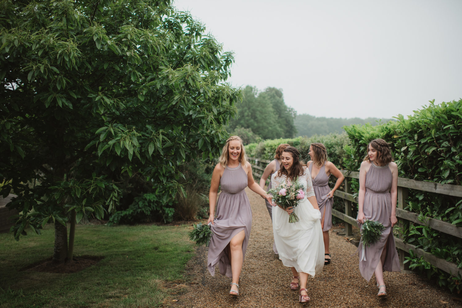 bride walking with lilac bridesmaids in the rain in norfolk countryside