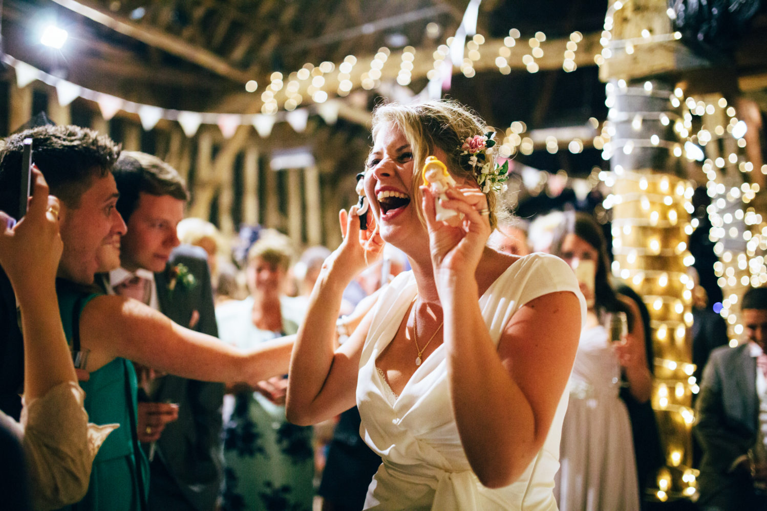 bride laughing at cake toppers surrounded by fairy lights at blackthorpe barn