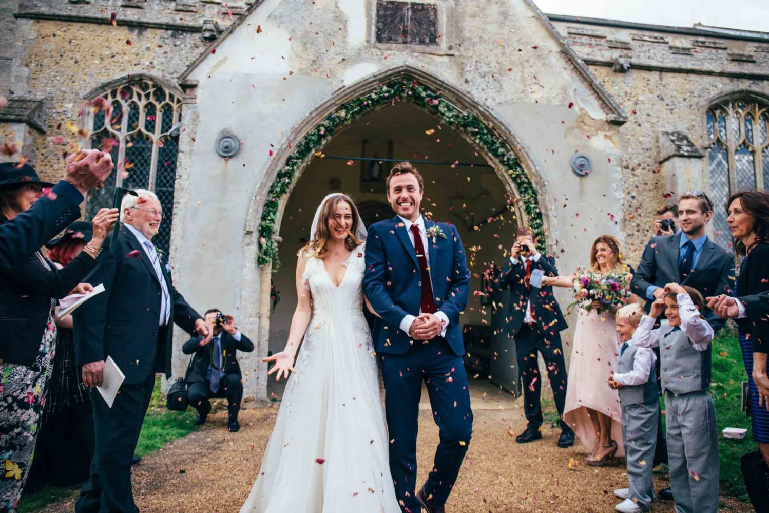 suffolk norfolk bride and groom grinning at confetti throwing outside church