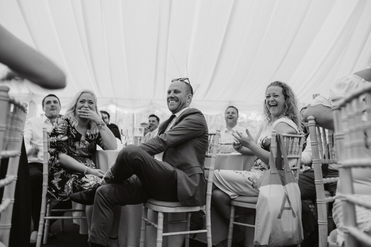 guest laughing in marquee at HOCKERING HOUSE WEDDING PHOTOGRAPHY NORFOLK