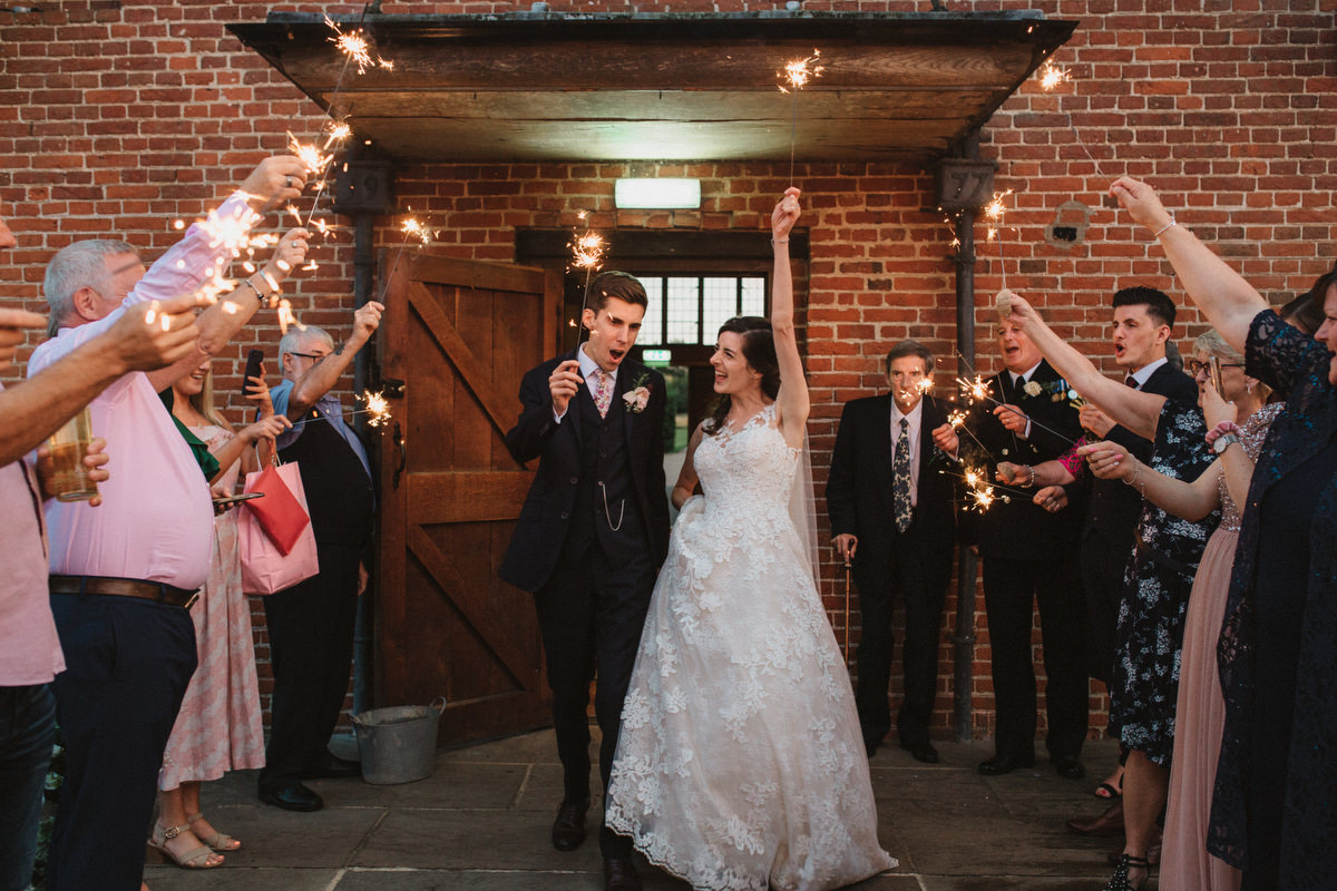 bride and groom with sparklers outside HAUGHLEY PARK BARN WEDDING PHOTOGRAPHY