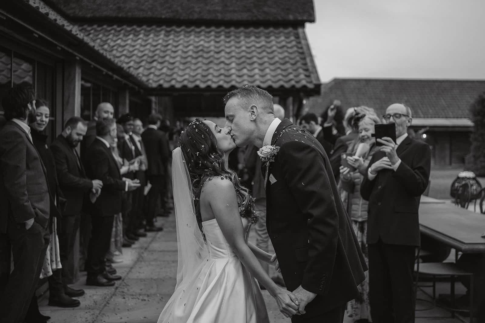 Black and white photo of confetti at wilderness reserve suffolk, bride and groom kissing